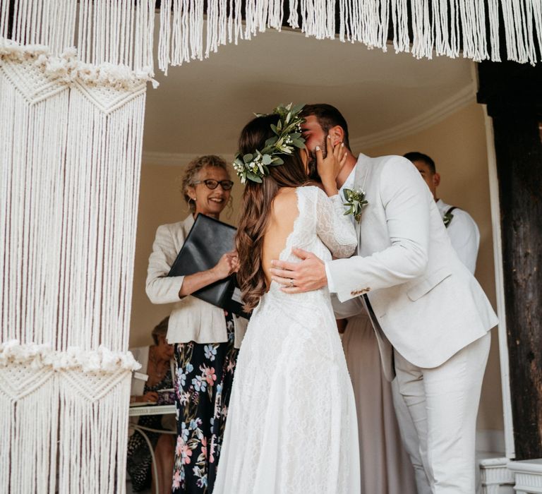 Bride and groom kiss under macrame altar decor