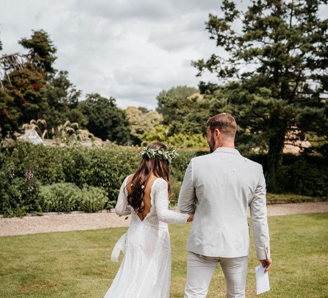 Low back lace wedding dress and pale linen suit for groom