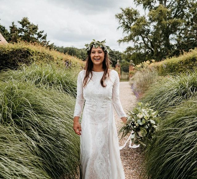 Bride in sleeved lace wedding dress with flower crown and foliage bouquet