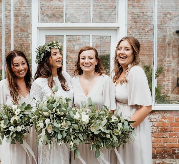 Neutral bridesmaid dresses with foliage bouquets at wedding with donut wall