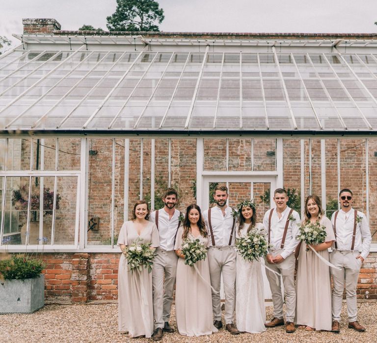 Bridal party and groomsmen in neutral outfits with foliage bouquets