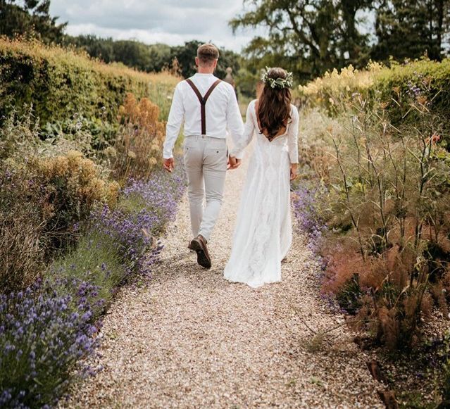 Bride and groom walk through walled garden