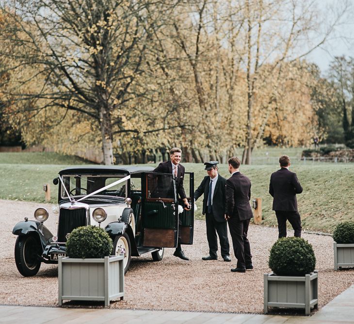 Groom in Moss Bros. Suit Getting Out of a Classic Wedding Car