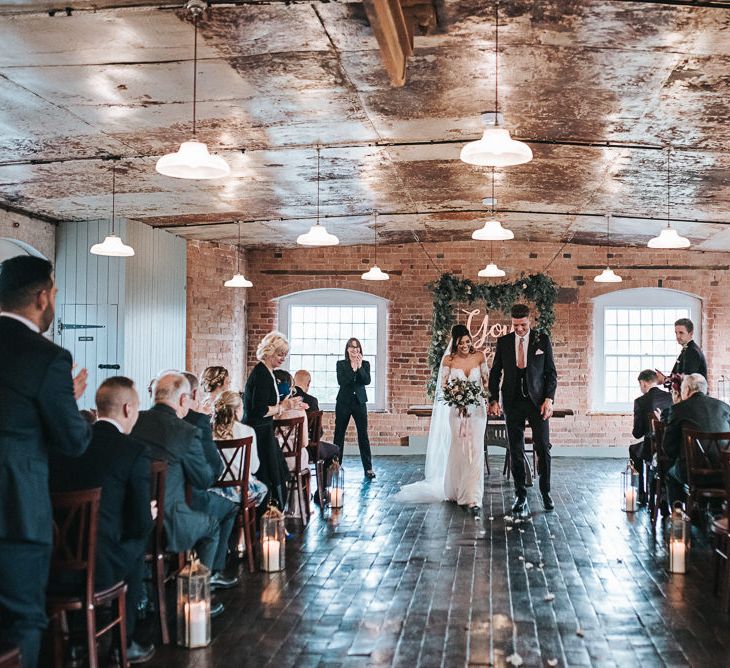 Stylish Bride in Pronovias Dracma Bardot Wedding Dress and Groom in Tailor Me Moss Bros. Suit Just Married