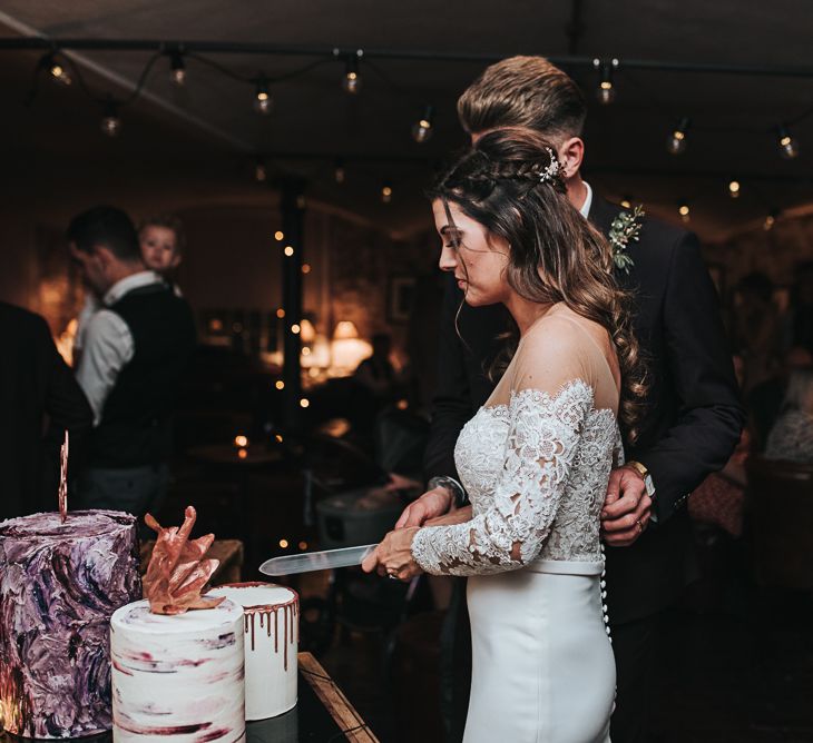 Cutting the Wedding Cake with Bride in Pronovias Dracma Bardot Wedding Dress and Groom in Tailor Me Moss Bros. Suit