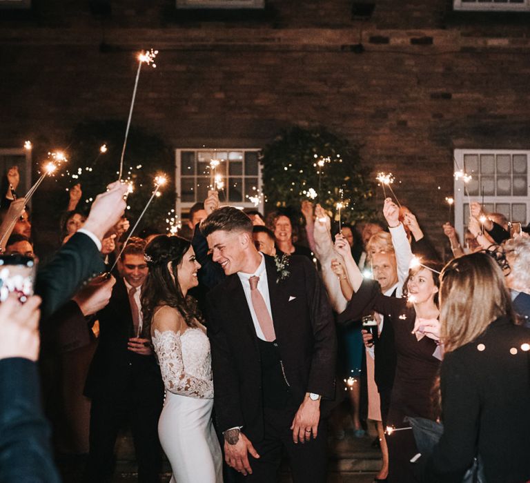 Sparkler Moment with Bride in Pronovias Dracma Bardot Wedding Dress and Groom in Tailor Me Moss Bros. Suit