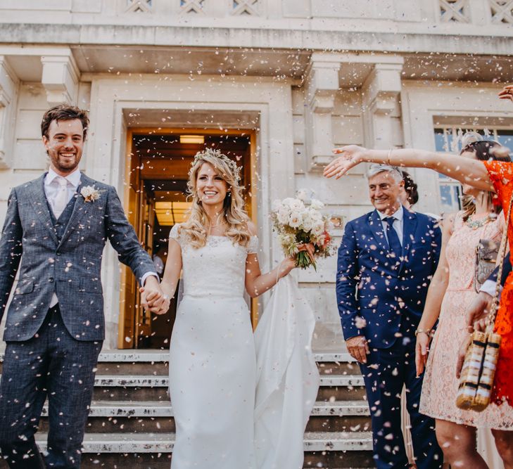 Confetti Moment with Bride in Lace Off The Shoulder Jennifer Regan Wedding Dress and Flower Crown and Groom in Grey Suit