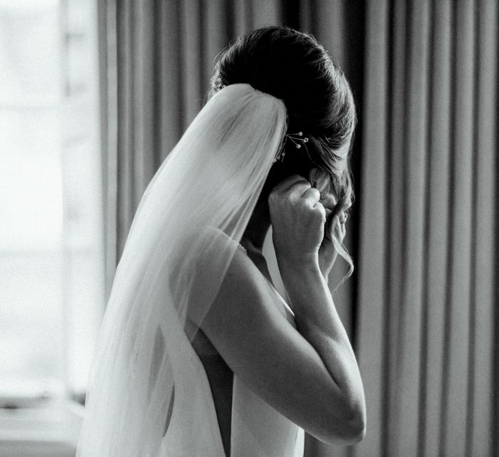 Wedding Morning with Bride Putting on Earrings Wearing a Cathedral Veil