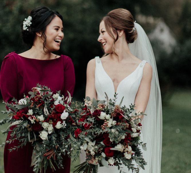 Bride in Essense of Australia Wedding Dress with Straps and Cathedral Length Veil and Bridesmaid in Burgundy Dress