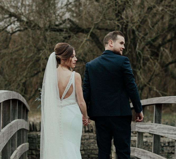 Bride in Essense of Australia Wedding Dress and Cathedral Veil and Groom in Marks and Spencer Suit Holding Hands