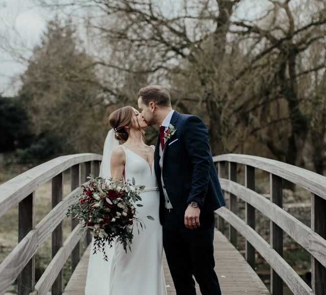 Bride in Essense of Australia Wedding Dress and Cathedral Veil and Groom in Marks and Spencer Suit Kissing