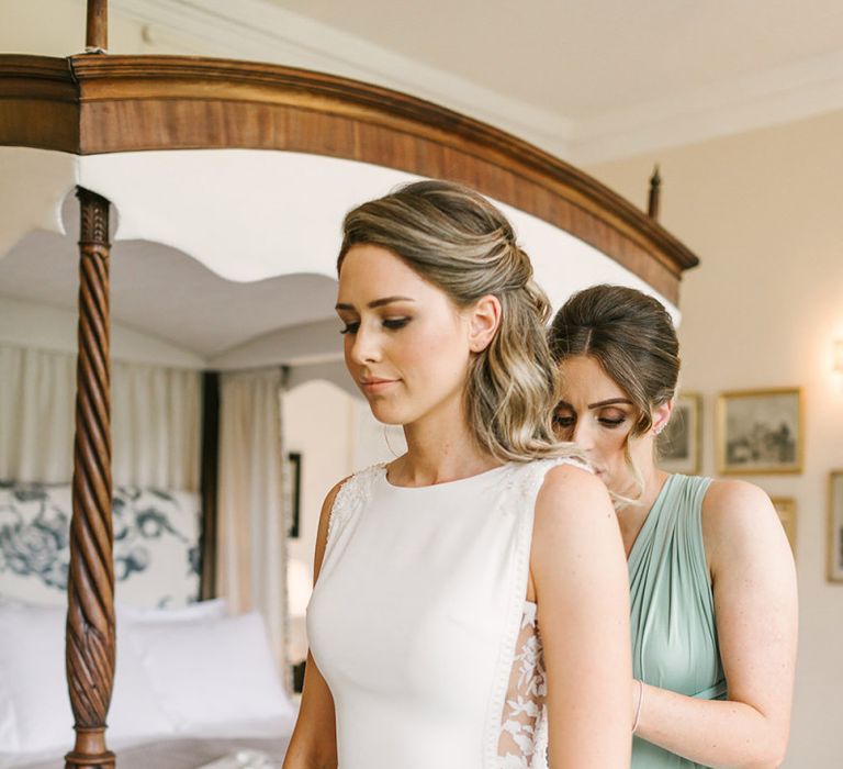 Bridesmaid Helping the Bride into Her Fitted Pronovias Wedding Dress with Lace Side Panels