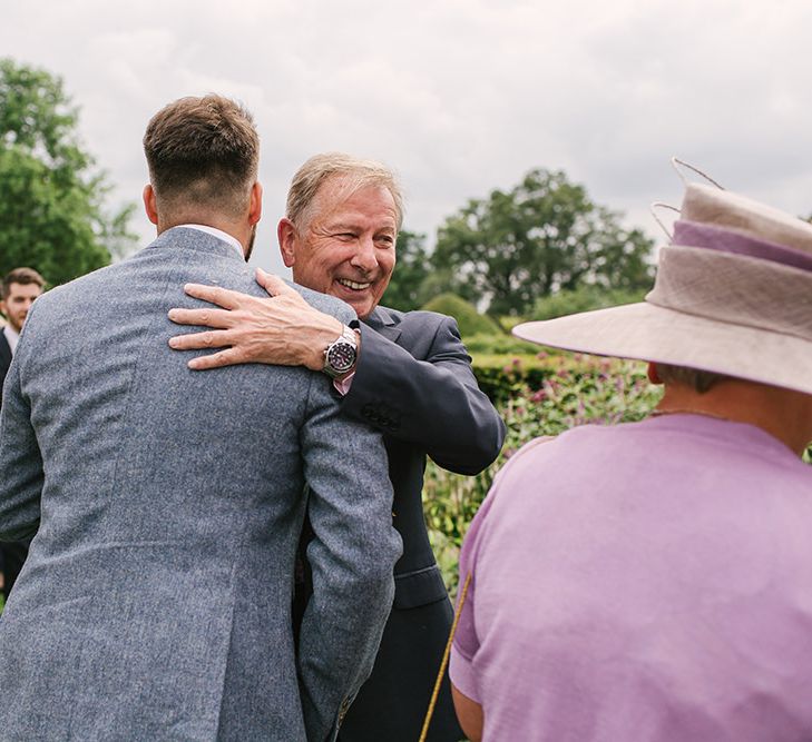 Groom in Grey Wedding Suit Being Congratulated by Wedding Guests