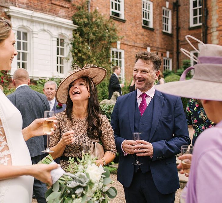 Bride in Pronovias Wedding Dress with Lace Side Panels Enjoying a Glass of Champagne with Wedding Guests