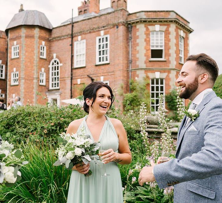 Groom in Grey Wedding Suit and Bridesmaids in Pale Green Multiway Dress Talking