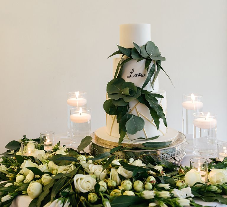 White Wedding Cake Surrounded by Foliage and Candles