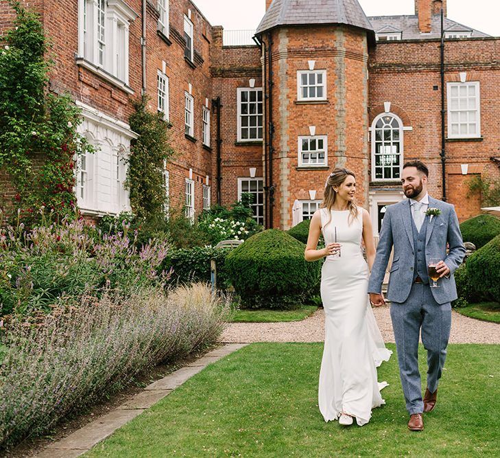 Bride in Pronovias Wedding Dress and Groom in Light Grey Wedding Suit Holding Hands Outside Iscoyd Park Wedding Venue