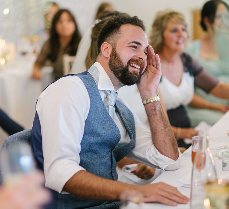 Groom in Grey Wool Waistcoat Laughing During the Wedding Reception Speeches