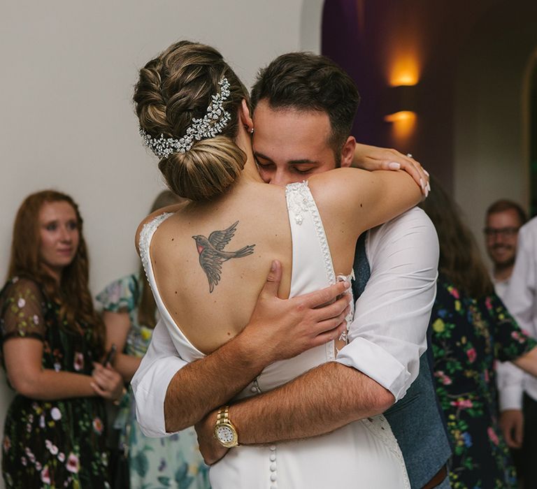 Groom Embracing His Bride in a Pronovias Wedding Dress with Rolled Up Hairstyle and Hair Vine