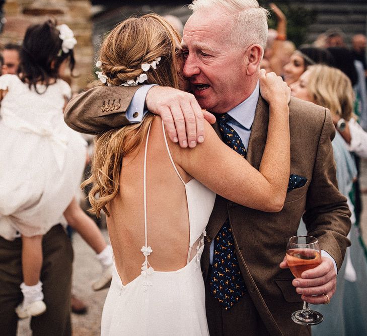 Bride removes outer layer of wedding dress to reveal thin strapped low back dress