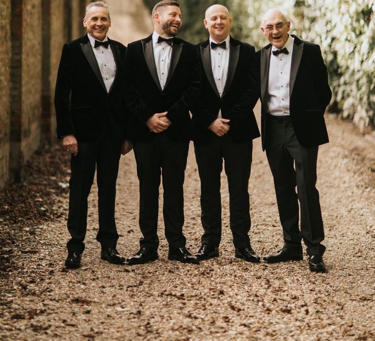 Groom and groomsmen in black tie tuxedo wedding suits