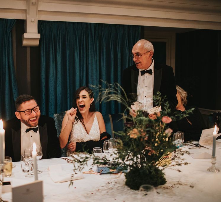 Bride and groom laugh at wedding speeches