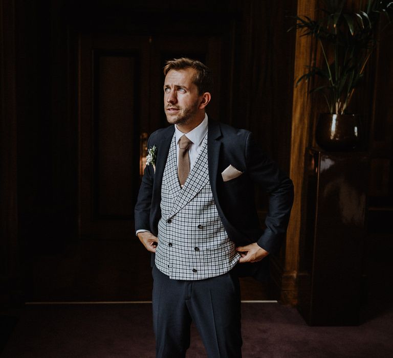 Groom in Navy Slim Fit Suit with Checked Double Breasted Waistcoat and Blush Pink Knitted Tie | Floral Arch and Bride in Batwing Sleeve Halfpenny Dress for London Pub Wedding | Caitlin + Jones