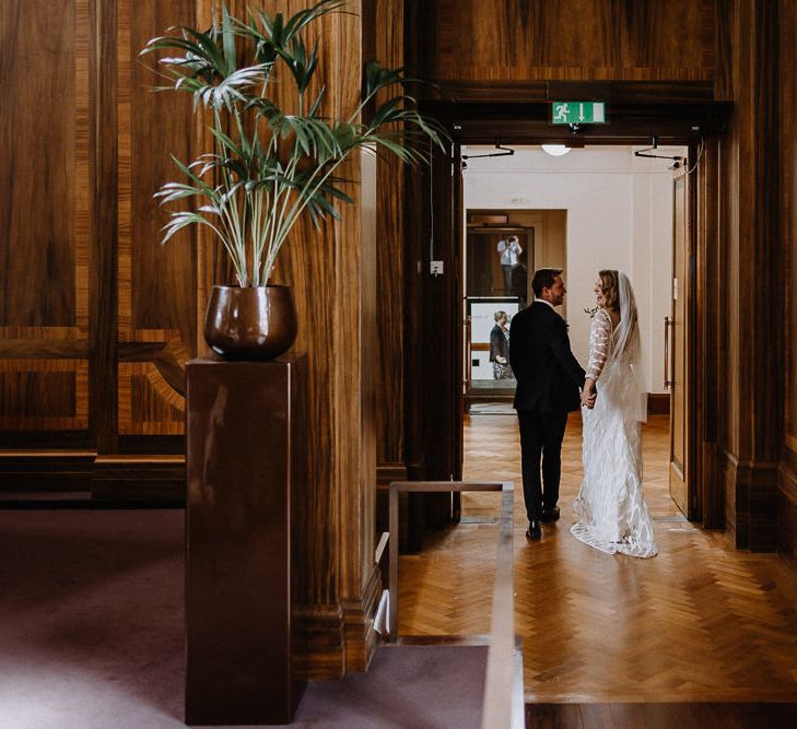 Bride in Embroidered Tulle Halfpenny London Dress with High Neckline, Batwing Sleeves and Low V-Back | Fingertip Length Veil from Florence &amp; Dot | Groom in Navy Slim Fit Suit with Checked Double Breasted Waistcoat and Blush Pink Knitted Tie | Wedding Ceremony at Stoke Newington Town Hall | Floral Arch and Bride in Batwing Sleeve Halfpenny Dress for London Pub Wedding | Caitlin + Jones