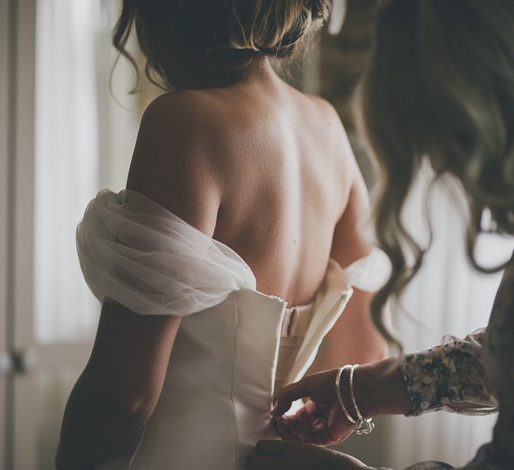 Bride gets into her off-the-shoulder wedding dress