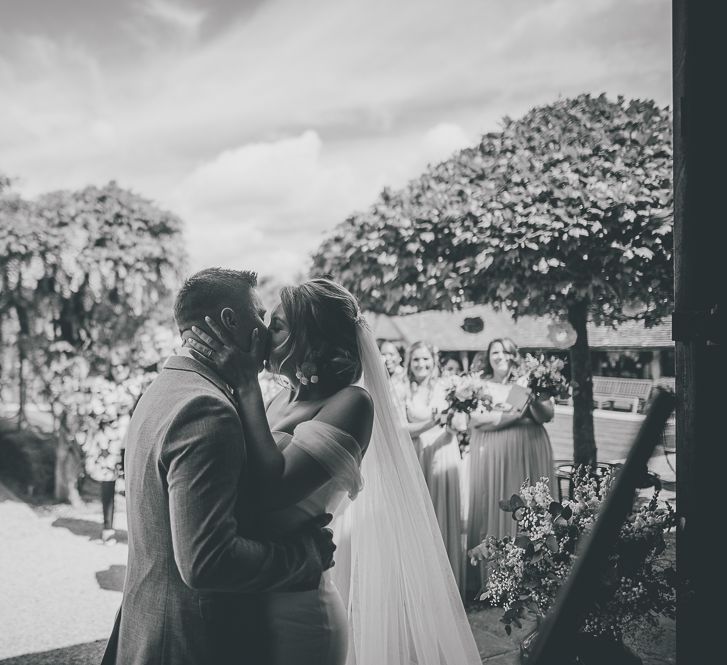 Bride kisses groom at outdoor rustic ceremony at Tythe Barn