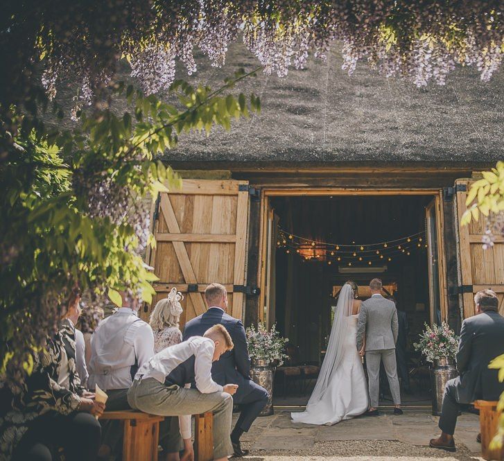 Stunning outdoor ceremony surrounded by purple wisteria at Tythe Barn