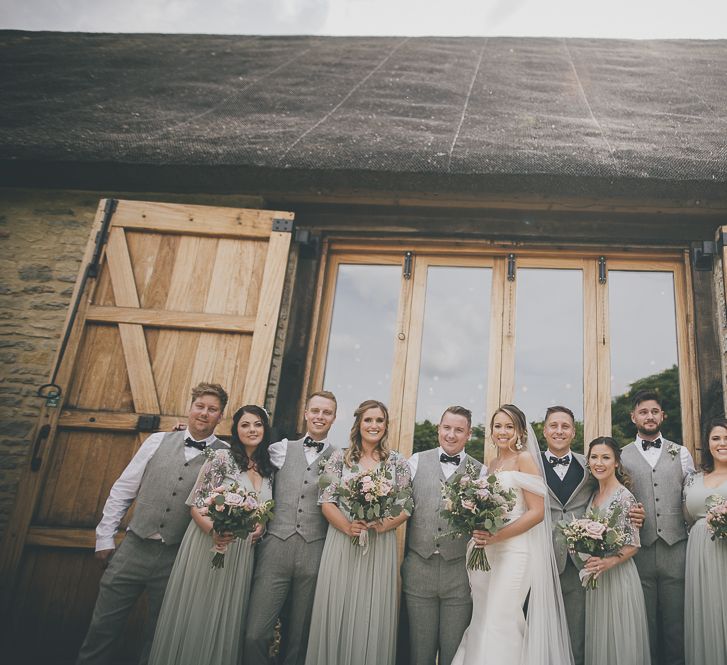 Bride in flat shoes with bridal party in embellished bridesmaid dresses and groomsmen in  matching waistcoats