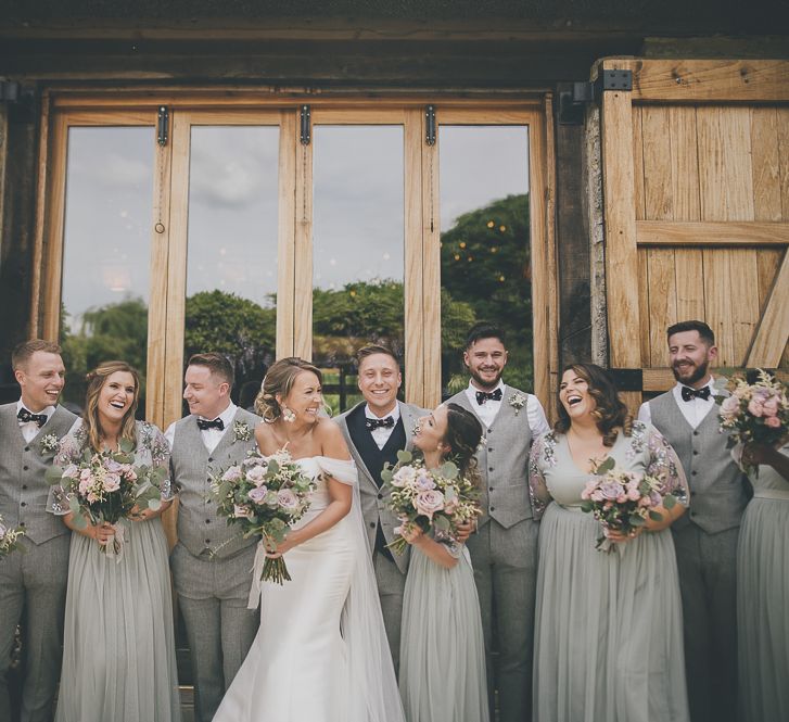 Bride in flat shoes with bridal party in embellished bridesmaid dresses and groomsmen in  matching waistcoats