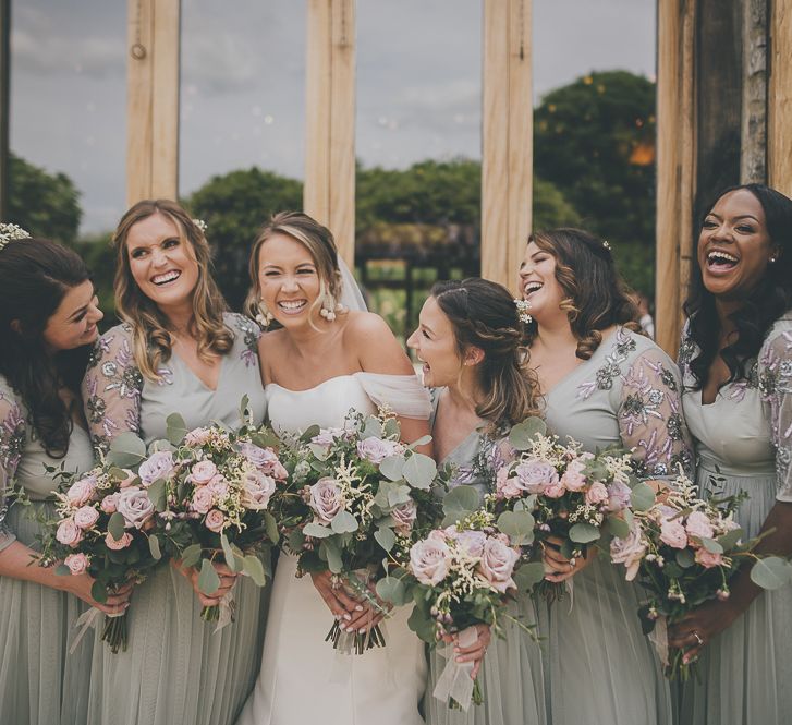 Bride in flat wedding shoes with bridal party with lilac wedding bouquets