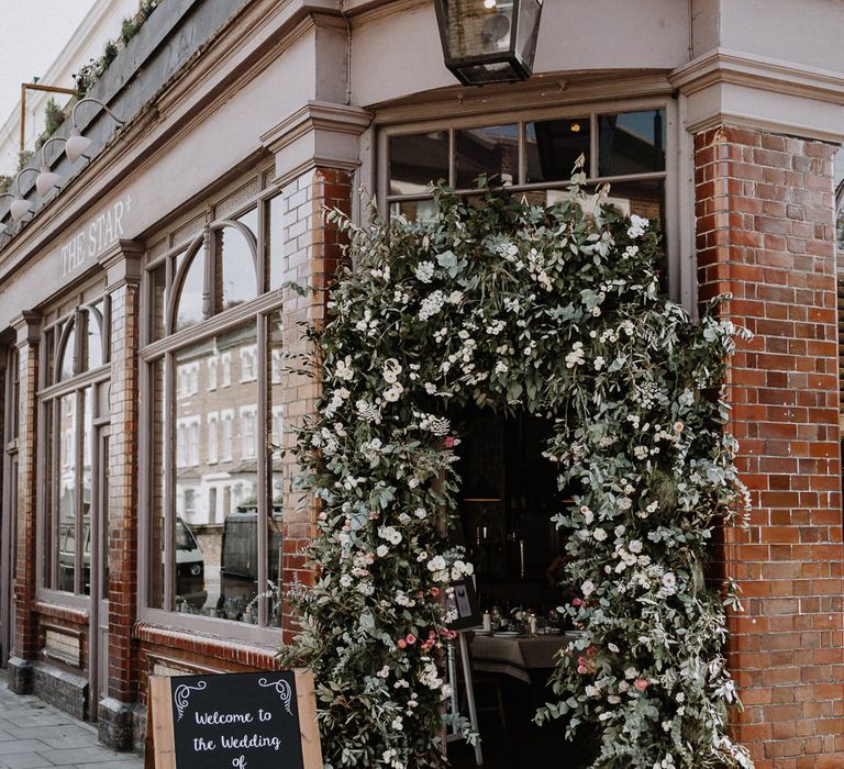 Floral Arch | Chalkboard Welcome Sign | Wedding Reception at The Star Pub, Highgate | Floral Arch and Bride in Batwing Sleeve Halfpenny Dress for London Pub Wedding | Caitlin + Jones