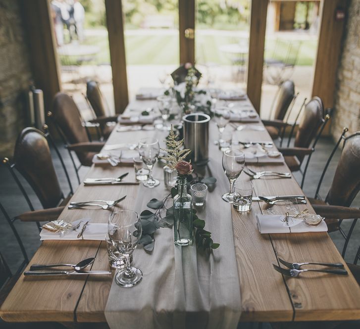 Single stem flowers in glass bottles at rustic wedding