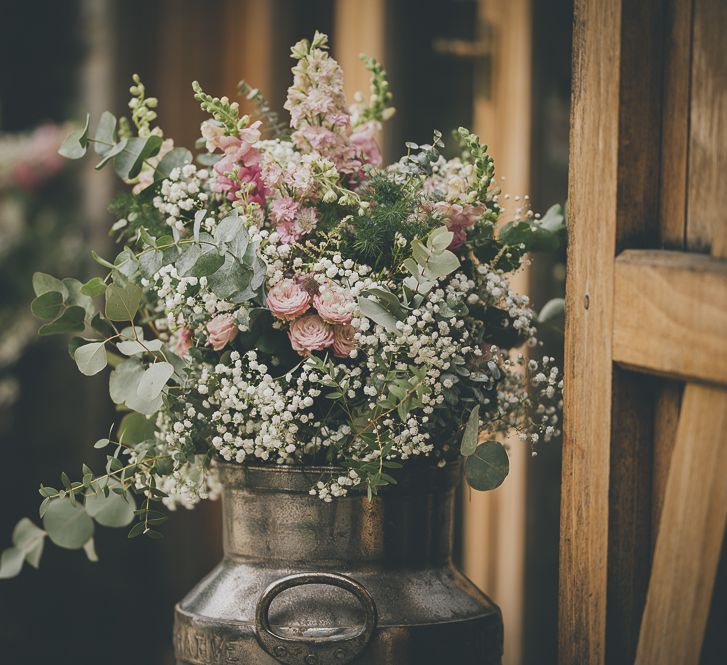 Rustic wedding flowers in milk churn for barn wedding