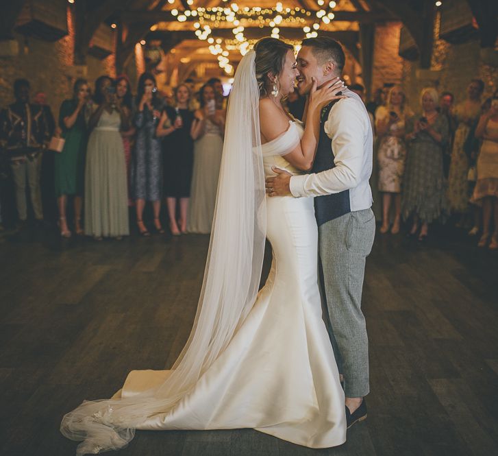 Bride in flat wedding shoes during first dance with new husband under fairy lights