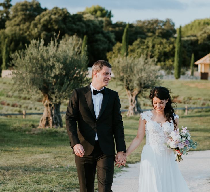 Bride in Appliqué Caroline Castigliano Wedding Dress and Groom in Tuxedo  Holding Hands