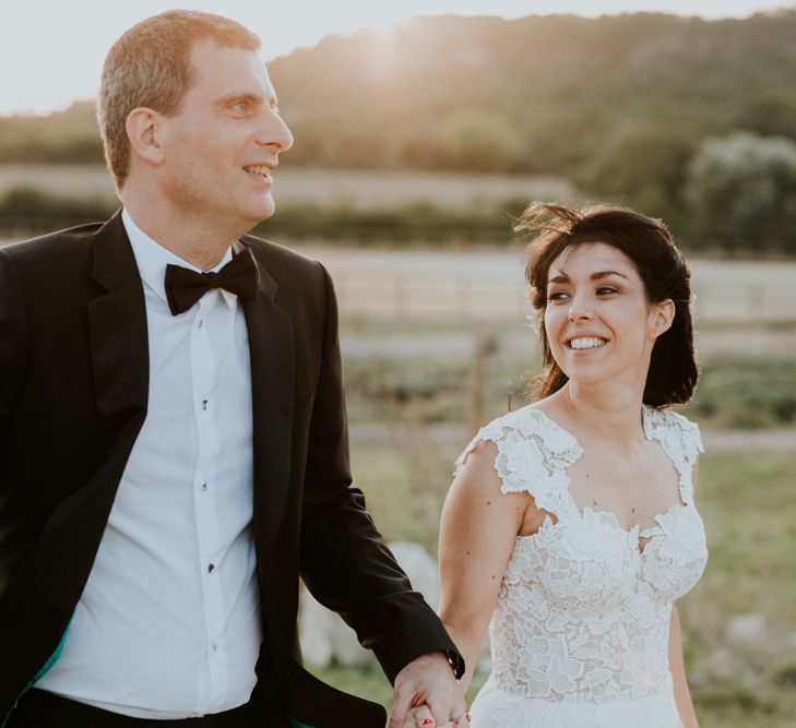 Golden Hour with Bride in Appliqué Caroline Castigliano Wedding Dress and Groom in Tuxedo Holding Hands