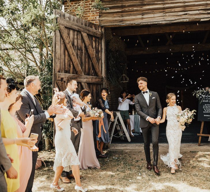 Confetti Moment | Bride in Embroidered Grace Loves Lace Gown with Fringing and Cut Out Back | Groom in Black Gagliardi Suit with Bow Tie and Braces | Bridal Bouquet of Mixed Ochre and White Flowers with Champagne Trailing Ribbon | Nude Strappy Nine West Shoes | Outdoor Ceremony at Fishley Hall with Grace Loves Lace Fringe Dress | Darina Stoda Photography