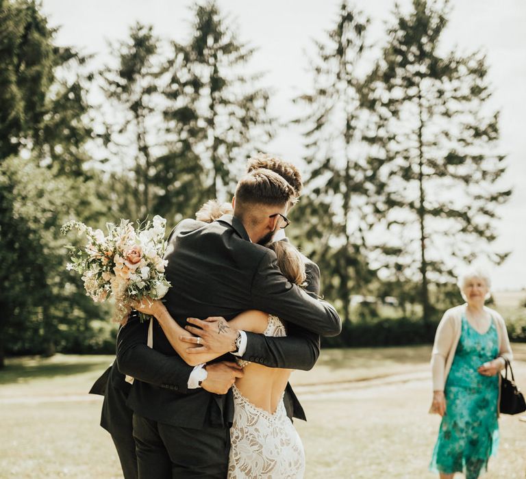 Bride in Embroidered Grace Loves Lace Gown with Fringing and Cut Out Back | Groom in Black Gagliardi Suit with Bow Tie and Braces | Bridal Bouquet of Mixed Ochre and White Flowers with Champagne Trailing Ribbon | Outdoor Ceremony at Fishley Hall with Grace Loves Lace Fringe Dress | Darina Stoda Photography