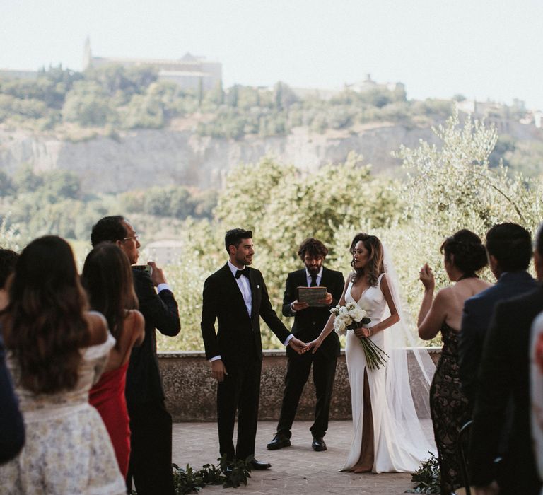 Wedding Ceremony | Bride in Silk Pallas Couture Wedding Dress with Plunging Neckline and Side Split | Roman &amp; French Cathedral Veil | Salvatore Ferragamo Nude Bridal Shoes | Long Stemmed Bridal Bouquet of White Flowers | Groom in Made to Measure Tuxedo Suit by Oscar Hunt | Black Aquila Shoes | Intimate Italian Castle Wedding with Prosecco Tower | James Frost Photography