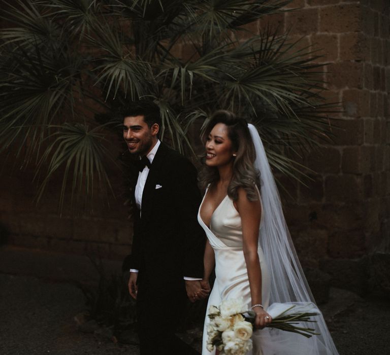 Bride in Silk Pallas Couture Wedding Dress with Plunging Neckline and Side Split | Roman &amp; French Cathedral Veil | Long Stemmed Bridal Bouquet of White Flowers | Groom in Made to Measure Tuxedo Suit by Oscar Hunt | Intimate Italian Castle Wedding with Prosecco Tower | James Frost Photography