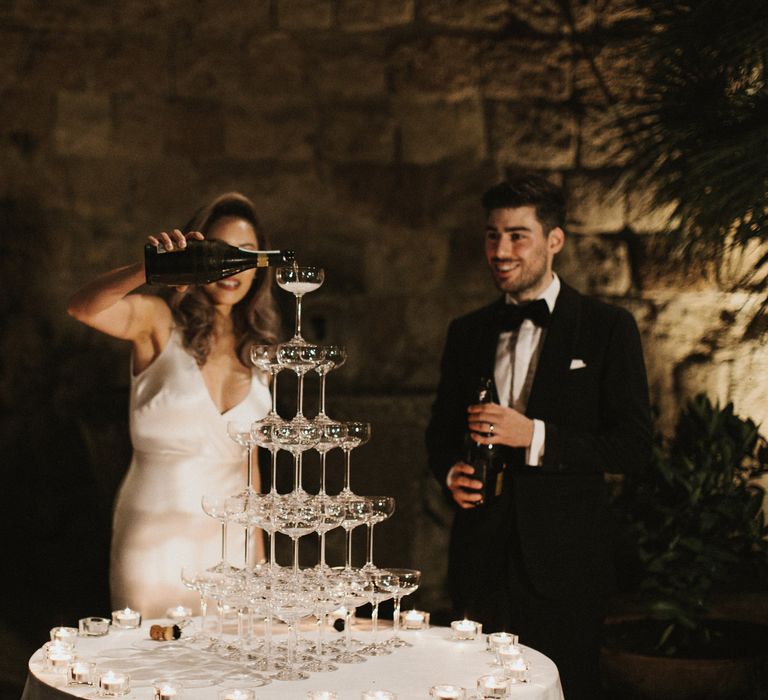 Prosecco Tower | Coupe Glasses | Tea Lights | Bride in Silk Pallas Couture Wedding Dress with Plunging Neckline and Side Split | Groom in Made to Measure Tuxedo Suit by Oscar Hunt | Intimate Italian Castle Wedding with Prosecco Tower | James Frost Photography