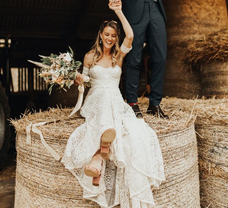 Bride in Rue de Seine Wedding Dress and Groom in Black Tie Suit Posing on a Hay Bale