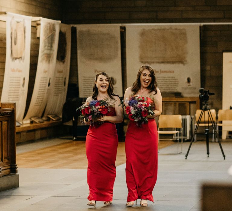 Bridesmaids in red dresses walking down the aisle