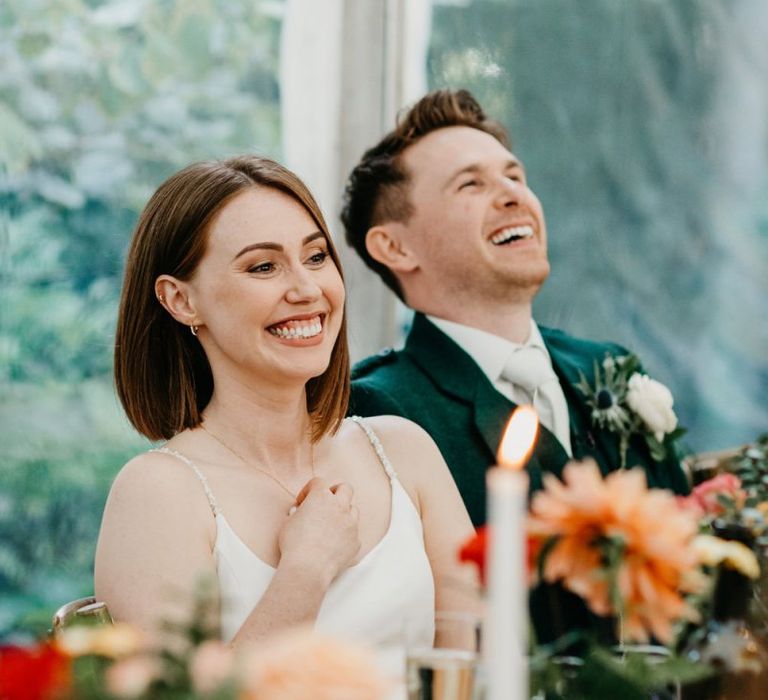 Bride and groom laughing during wedding reception speeches