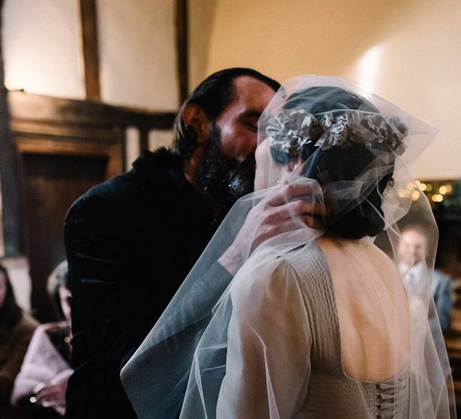 Bride wearing vintage styled floral headpiece with corset waist dress and groom in black suit