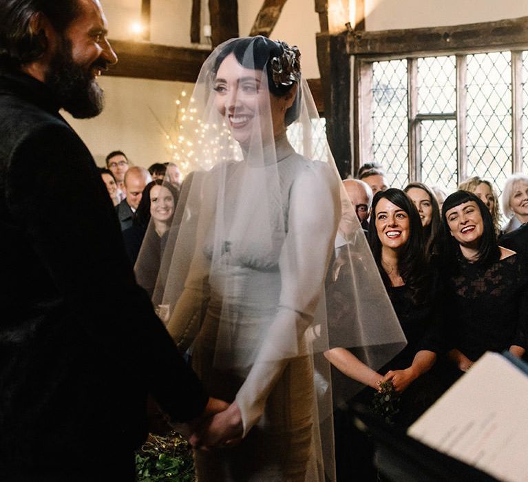 Bride wearing vintage styled floral headpiece with corset waist dress and groom in black suit